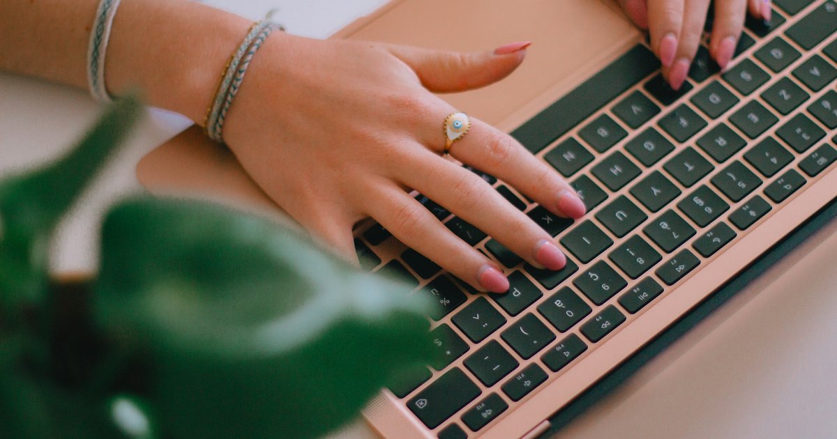 Hands typing on a laptop keyboard while registering a domain name.